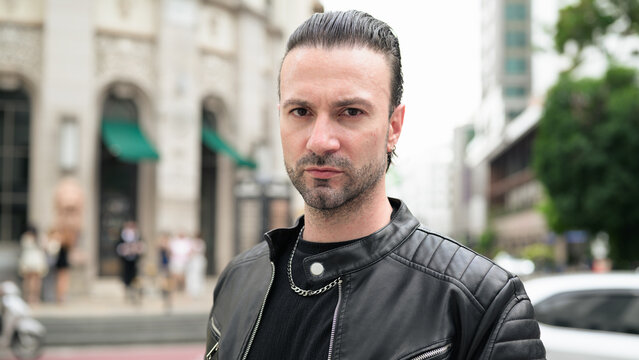 Fototapeta Handsome bearded man in black leather jacket posing in city streets