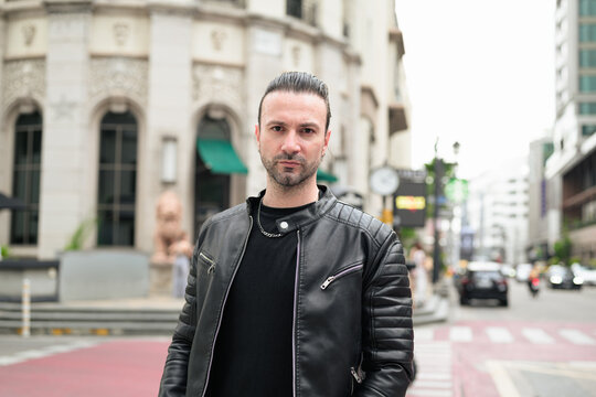 Fototapeta Handsome bearded man in black leather jacket posing in city streets