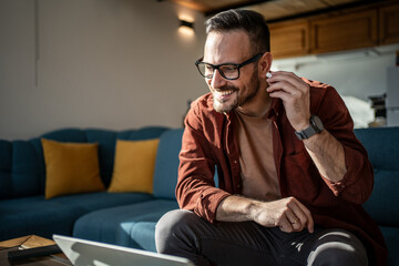 Man having video call with wireless earbuds working from home
