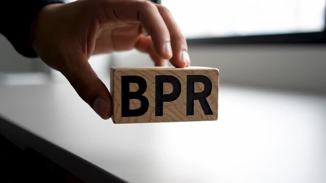 Wooden cube with the acronym BPR, representing Business Process Reengineering, is being held in the hand of a manager. This symbolizes the focus on innovation and effective management strategies