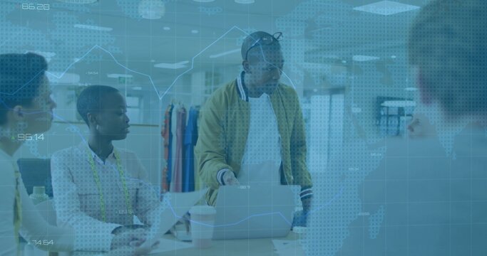 Leaning Black designer in mustard jacket guiding team at design studio table, with laptop, swatches - Powered by Adobe