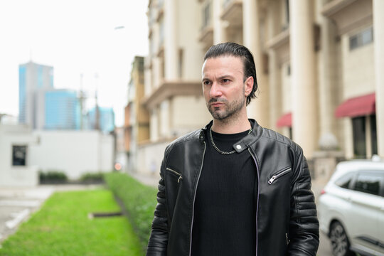 Fototapeta Handsome bearded man in black leather jacket posing in city streets