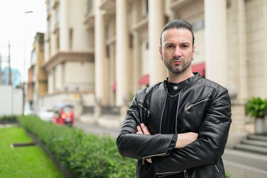 Fototapeta Handsome bearded man in black leather jacket posing in city streets