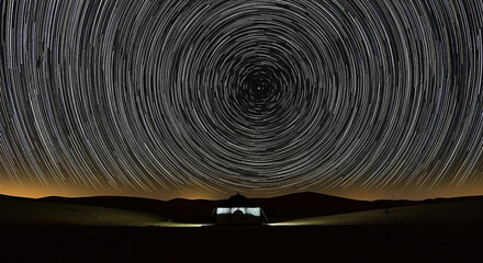 Circumpolar star trails above a tent in a desert landscape at night