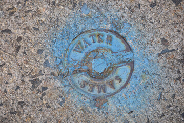 A Municipal Water Company Logo On A Pedestrian Sidewalk.