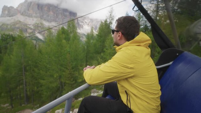 Traveler man wearing a yellow jacket riding a cable car near the Cinque Torri in the Dolomites, Italy.Travel adventure in the Alps and Dolomites surrounded by mountains