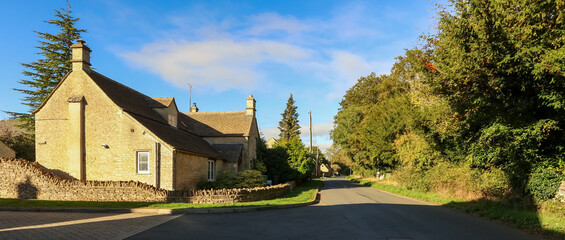 Fototapeta premium Cotswolds village house with traditional stone architecture along a winding road, embodying rural England life