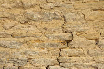 Stone masonry wall showing rustic texture and weathered surface with rough mortar joints, creating a strong background pattern