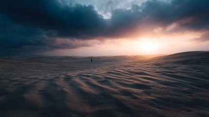 Naklejka premium A lone silhouette traverses vast rippling sand dunes under a dramatic glowing sunset sky