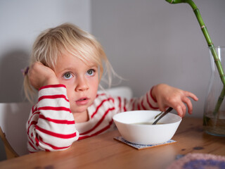 Girl sitting at the table with an empty soup bowl waiting for more