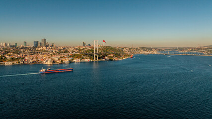Aerial view of the Bosphorus Bridge with drone on a cloudy day. Tanker ship passing under the FSM Bridge with a heavy car traffic on the bridge.Aerial view of The Second Bosphorus Bridge.