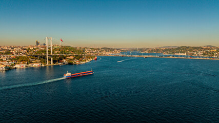 Aerial view of the Bosphorus Bridge with drone on a cloudy day. Tanker ship passing under the FSM Bridge with a heavy car traffic on the bridge.Aerial view of The Second Bosphorus Bridge.