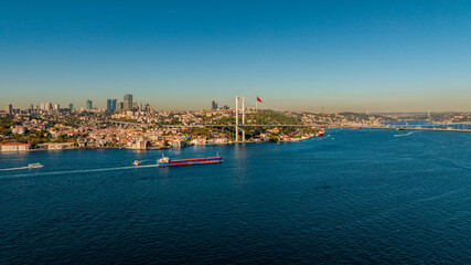 Aerial view of the Bosphorus Bridge with drone on a cloudy day. Tanker ship passing under the FSM Bridge with a heavy car traffic on the bridge.Aerial view of The Second Bosphorus Bridge.