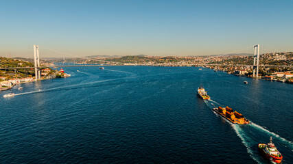 Aerial view of the Bosphorus Bridge with drone on a cloudy day. Tanker ship passing under the FSM Bridge with a heavy car traffic on the bridge.Aerial view of The Second Bosphorus Bridge.
