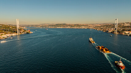 Aerial view of the Bosphorus Bridge with drone on a cloudy day. Tanker ship passing under the FSM Bridge with a heavy car traffic on the bridge.Aerial view of The Second Bosphorus Bridge.