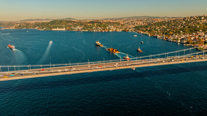 Aerial view of the Bosphorus Bridge with drone on a cloudy day. Tanker ship passing under the FSM Bridge with a heavy car traffic on the bridge.Aerial view of The Second Bosphorus Bridge.