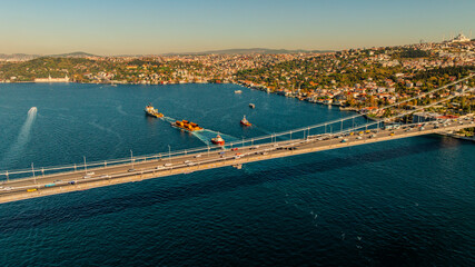 Aerial view of the Bosphorus Bridge with drone on a cloudy day. Tanker ship passing under the FSM Bridge with a heavy car traffic on the bridge.Aerial view of The Second Bosphorus Bridge.