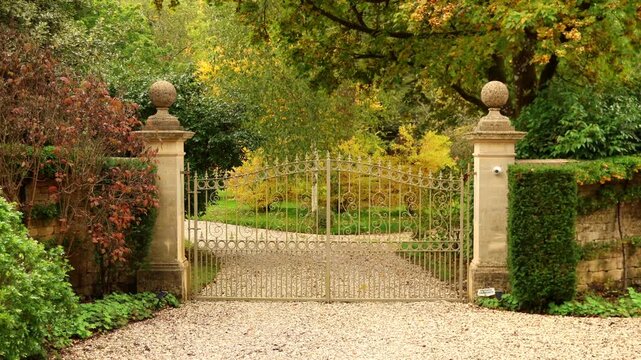 Elegant wrought iron gate opening in the Cotswolds. Cotswolds countryside, England