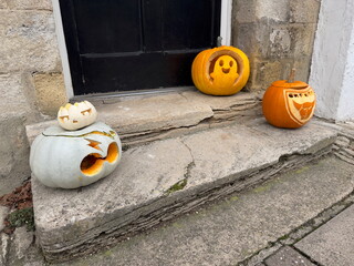 Different coloured carved pumpkins with faces sat on an outside door step ready for Halloween celebrations.UK