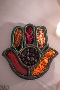 Assortiment d'entr&eacute;es et condiments servi dans un plat artisanal en forme de Main de Fatma