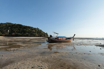 Obraz premium peaceful coastal scene from Phi Phi Island, Thailand, showing a single wooden boat resting on its side on the exposed seabed during low tide of the Andaman Sea