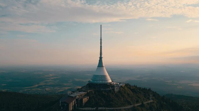 Experience the beauty of Jested Mountain in Czechia as the sun sets behind the iconic tower. Aerial shots capture the serene landscape and the hotel nestled in the hills of Liberec.