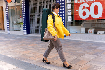 Woman musician walking urban street carrying violin case © Alfonso Soler