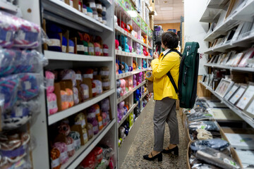 Woman shopping for yarn in store with violin
