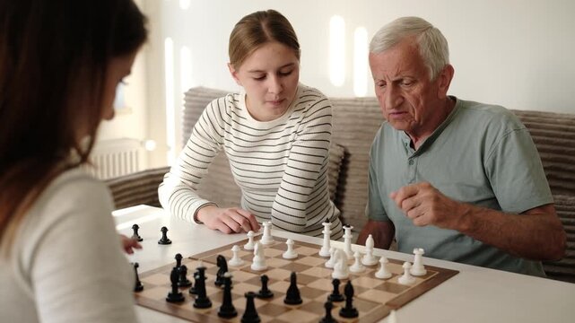 Grandfather Playing Chess With Granddaughters At Home