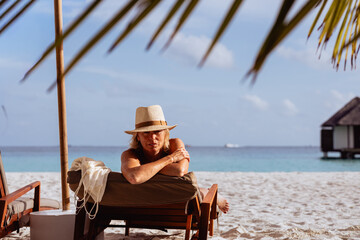 Elegant woman relaxing on beach lounge chair enjoying tropical vacation