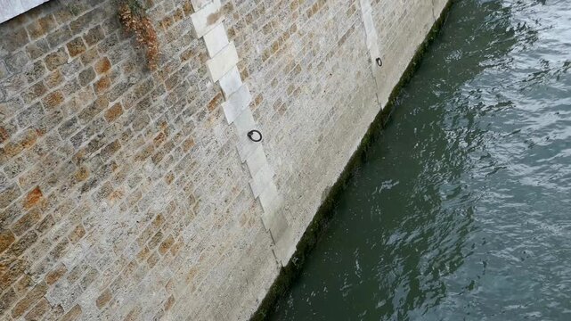 Brick wall on side of river in Paris with water waves