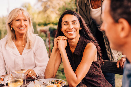 Food bowls and beer bottle kept on table with family spending leisure time at social gathering party in background