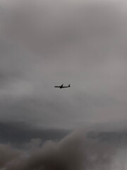 Lonely airplane in a cloudy sky, black and white minimalist photo 