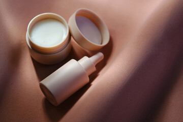 Face cream and serum on a soft beige background.