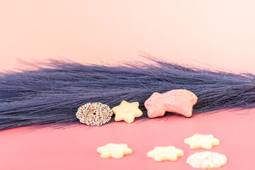 Christmas cookies with blue feathers on pink background with text space