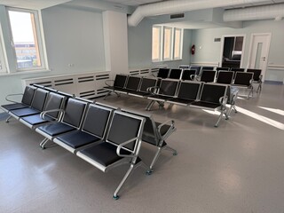 Empty, modern waiting room with multiple rows. Minimalist space is characteristic of a hospital, clinic, government building, business office, or transportation terminal.