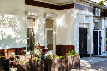 Woman enjoying a warm afternoon while working at an outdoor cafe with plants