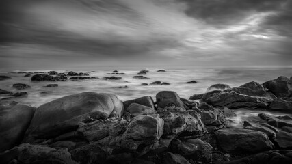 Dramatic Black and White Seascape with Rocky Shore and Cloudy Sky