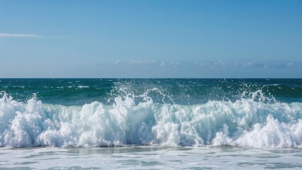 Vibrant ocean waves crashing on the shore with a clear blue sky in the background.