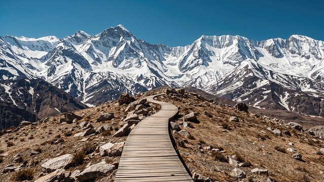 Snow-capped mountains with a winding wooden path through rocky terrain. - Powered by Adobe