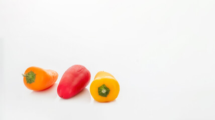 Close-up of three colorful sweet peppers (orange, red, and yellow) isolated on a white background.