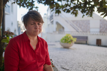 Upset overweight woman sitting alone outdoors