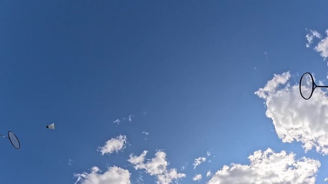 People hit the shuttlecock with bambintome rackets against the sky. Street game. The racket hits the shuttlecock.