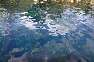 calm freshwater surface with rocky features, transparent water showcasing submerged stones and gentle waves