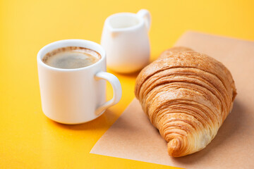 Tasty french croissant and black coffee on yellow background