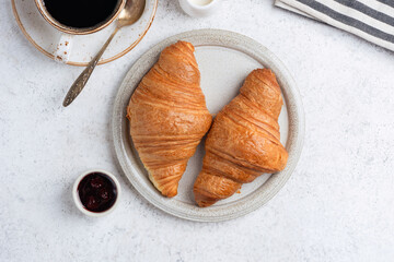 Two Tasty french croissants and black coffee on grey stone background, top view