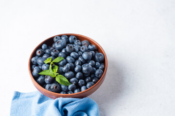 Fresh organic blueberries in bowl on grey stone background