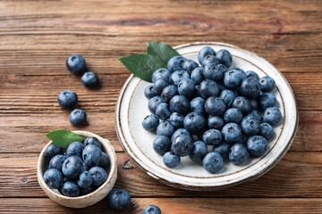 Fresh berries harvest. Group of blueberries in bowl on wooden table
