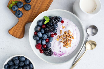 Blueberry acai yogurt bowl with berries and granola, table top view. Clean eating, diet meal