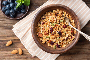 Homemade granola with dried fruits, pumpkin seeds and almond nuts in wooden bowl. Healthy food